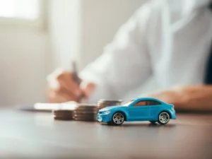 man fills in forms with car next to a pile of cash