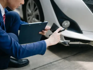 man with clipboard takes photos of car accident