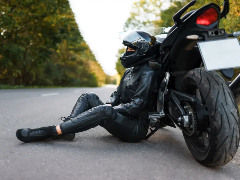 motorcyclist sat on road next to motorbike