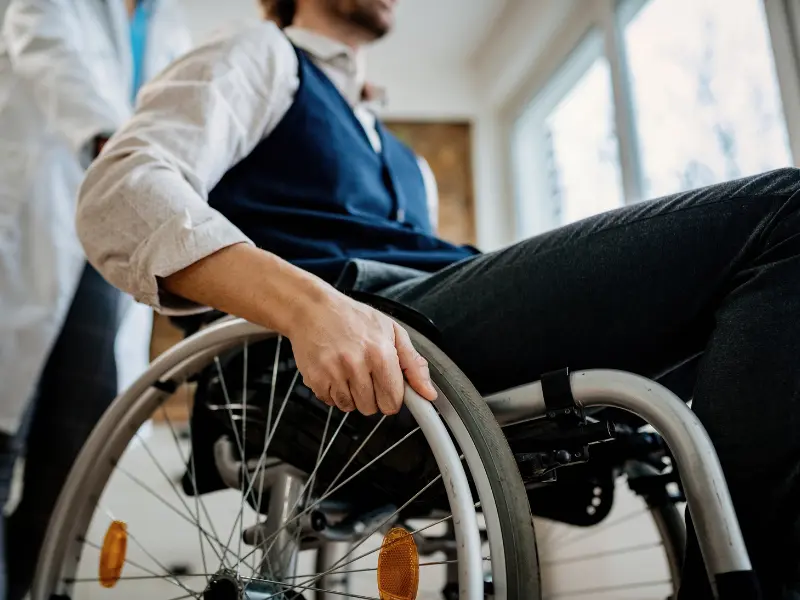man in a shirt using a wheelchair with medical professional behind
