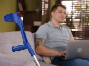 man with crutch works on a laptop